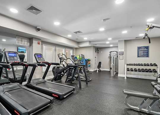 A gym with treadmills, weights, and exercise equipment.