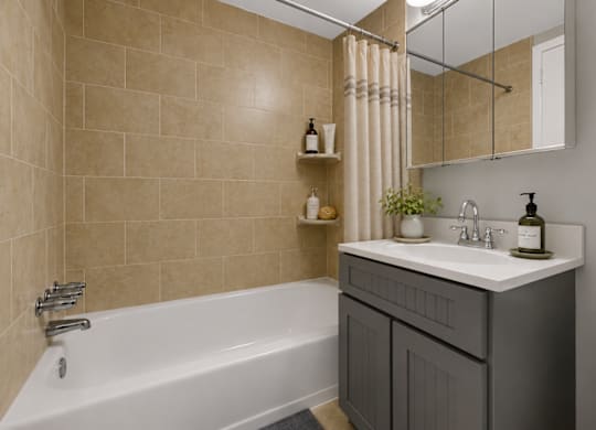 A bathroom with a white bathtub, a sink with a mirror above it, and a toilet.