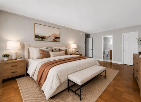 A bedroom with a large bed, a bench, and a painting on the wall.