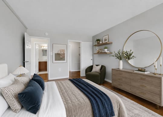 A bedroom with a large bed and a dresser with a mirror.