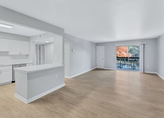 the living room and kitchen of a new home with white cabinets and a large window