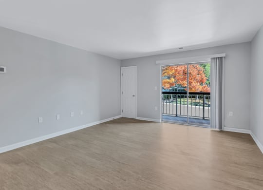 the living room of an empty house with a door to a balcony