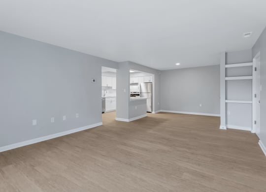 a living room and kitchen with a wood floor and grey walls