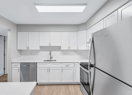 a white kitchen with stainless steel appliances and white cabinets