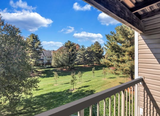the view from the balcony of a house overlooking a yard and trees