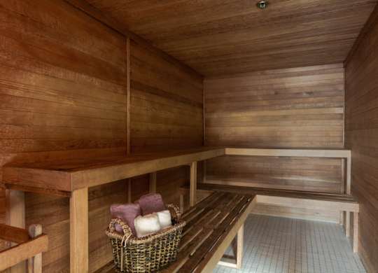 A wooden sauna with a bench and a basket of towels.
