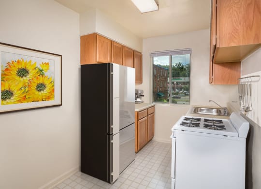 a kitchen with white appliances and a painting of sunflowers
