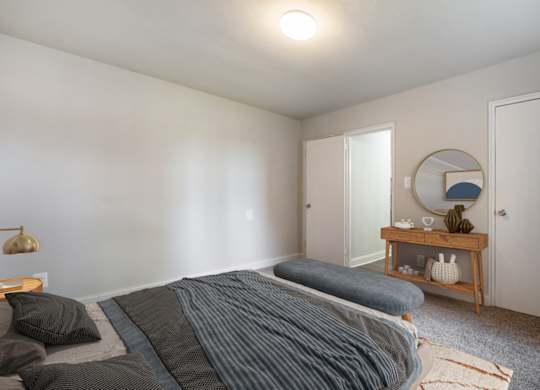 A bedroom with a bed, a nightstand, and a mirror.
