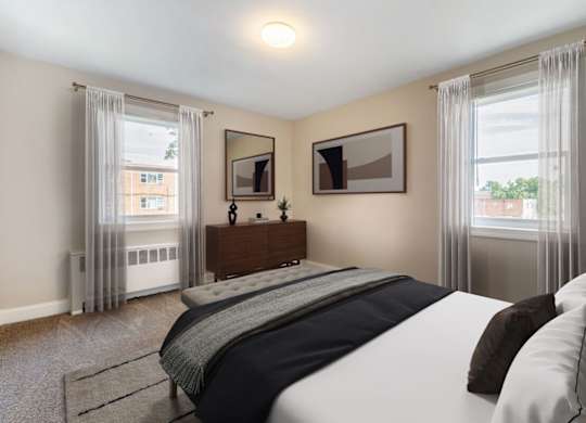A bedroom with a large bed and a window with curtains.