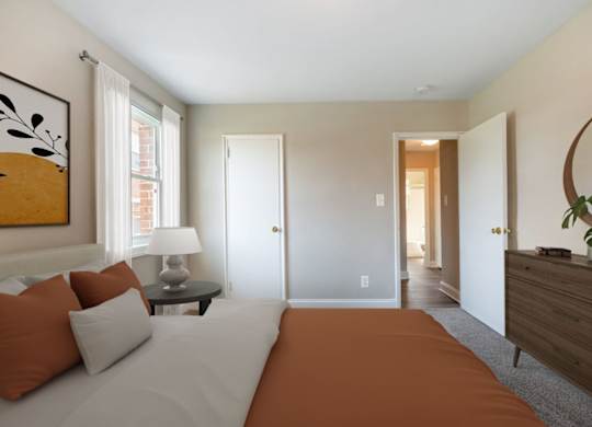 A bedroom with a bed, nightstand, lamp, and a painting on the wall.