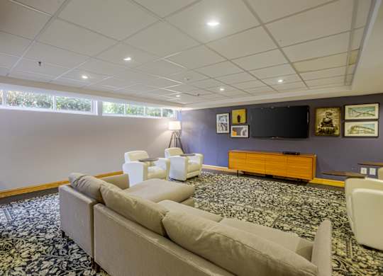 A living room with a couch, chairs, and a television.