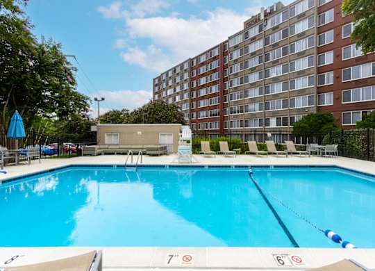 A large swimming pool in front of a red brick building.