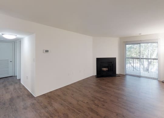 an empty living room with wood floors and a fireplace