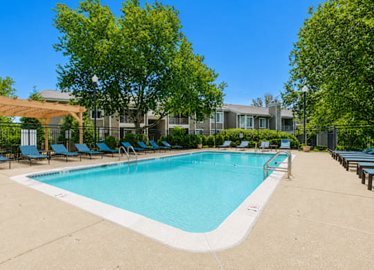 A large swimming pool surrounded by trees and lounge chairs.