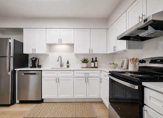 A modern kitchen with white cabinets and stainless steel appliances.