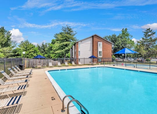 a swimming pool with chaise lounge chairs and umbrellas in front of a brick building