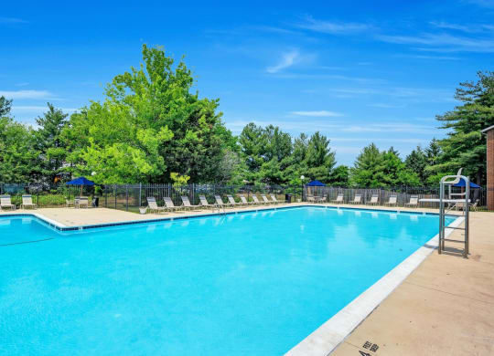 a swimming pool with chairs and trees in the background
