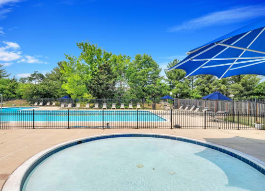 a swimming pool with a blue umbrella and trees in the background