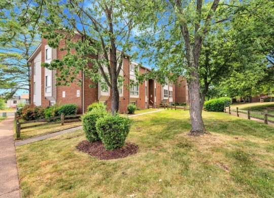 a grassy area with trees in front of a brick building
