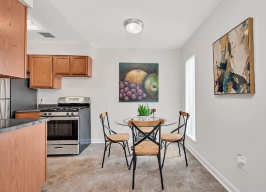 a dining area with a table and chairs and a kitchen in the background