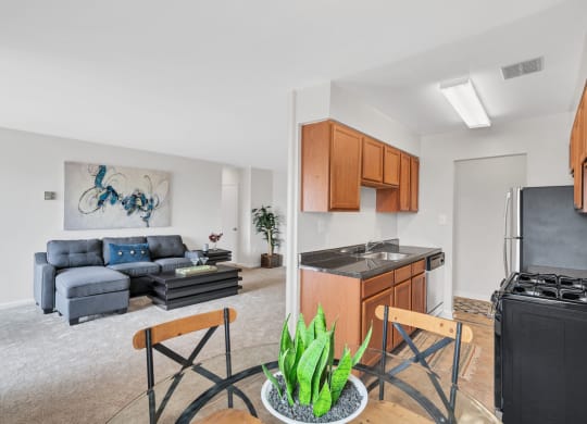 a living room with a couch and a table with two chairs and a kitchen with a stove