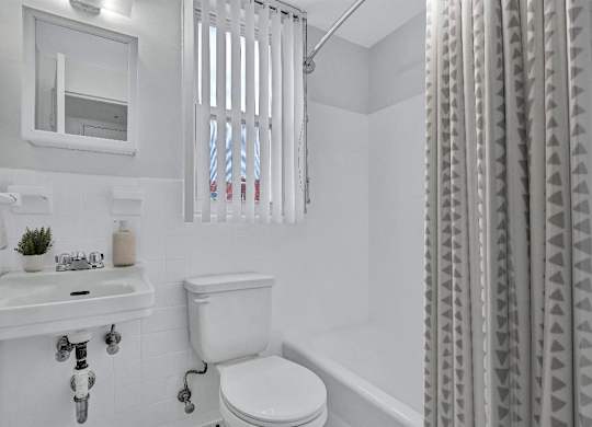 A white bathroom with a toilet, sink, and shower curtain.