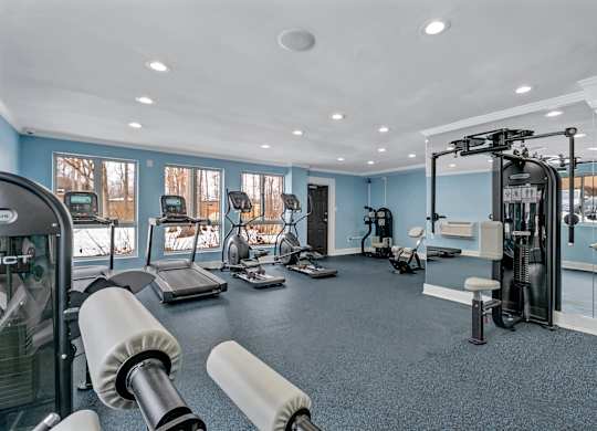 A gym with a variety of equipment including treadmills, weights, and exercise machines.