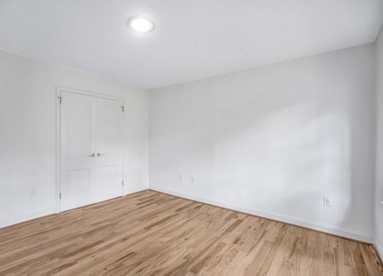 A room with a white door and wooden flooring.