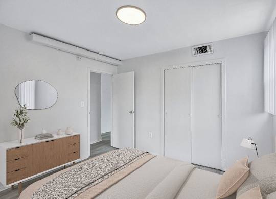 A bedroom with a bed, dresser, and mirror.