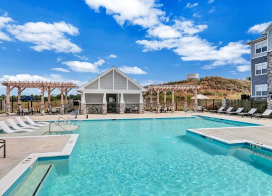 a swimming pool with chairs and a building in the background