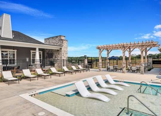 a swimming pool with chaise lounge chairs and a house in the background