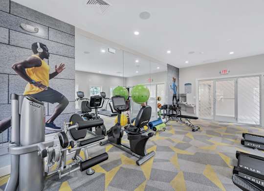 a gym with cardio equipment and a man running on a treadmill