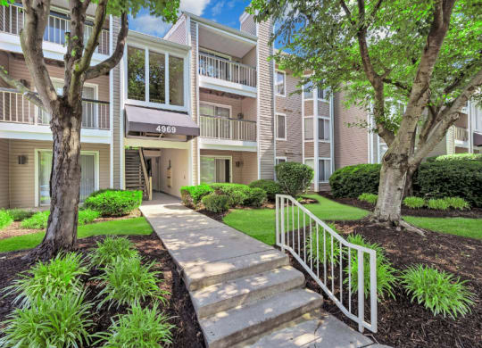 a stairway leading up to an apartment building with trees