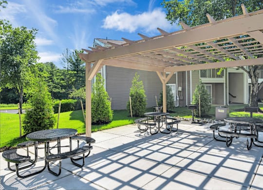 a patio with tables and chairs under a wooden pergola