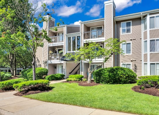an apartment building with a lawn and trees in front of it