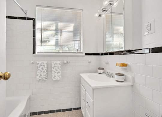 A white bathroom with a white sink and a white tub.