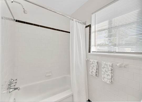 A white bathroom with a tub and a window.