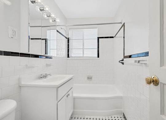 A white bathroom with a tub, sink, and toilet.