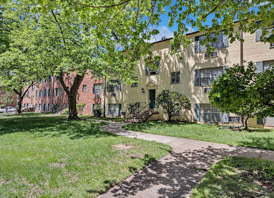 A tree-lined walkway leads to a building.