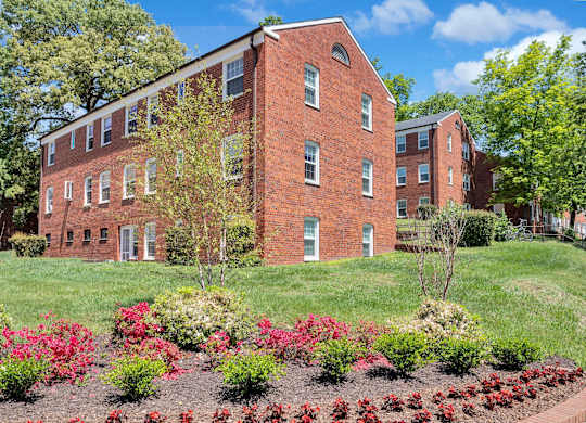 A red brick building with a garden in front.