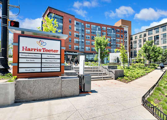 A Harris Teeter sign is in front of a building with a walkway and trees.