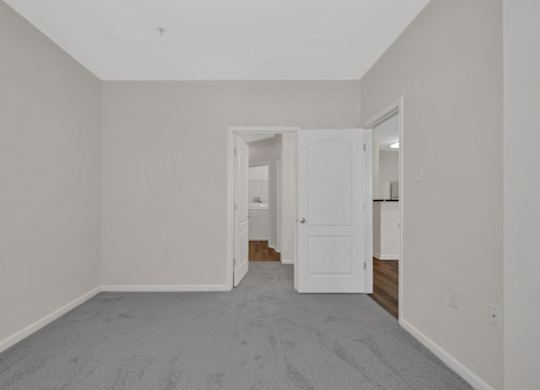 A room with a carpeted floor and a white door.