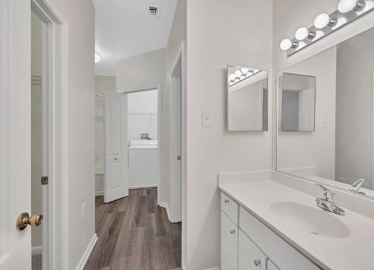 A bathroom with a sink, mirror, and lighting fixture.