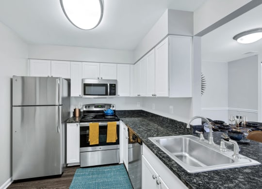 Renovated kitchen at Waterside at Reston with white cabinets, granite countertops and stainless steel appliances.