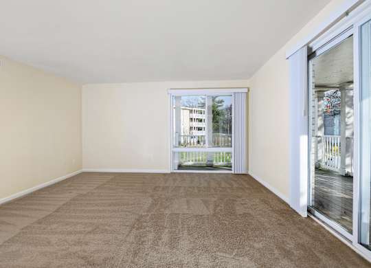 a living room with carpet and sliding glass doors to a balcony