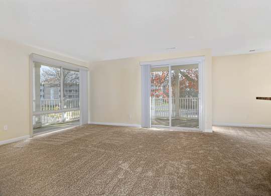 an empty living room with sliding glass doors to a balcony