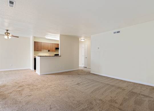 an empty living room and kitchen with a ceiling fan