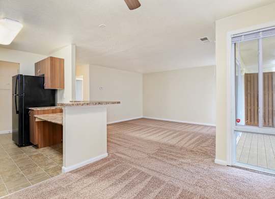 an empty living room and kitchen with a sliding glass door