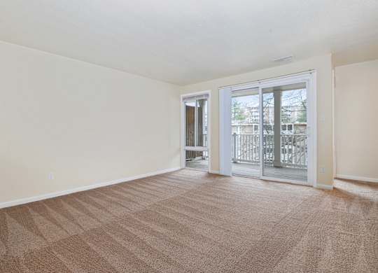 an empty living room with a sliding glass door to a balcony