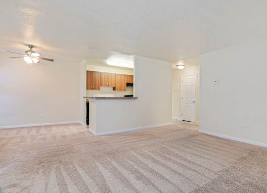an empty living room and kitchen with a ceiling fan